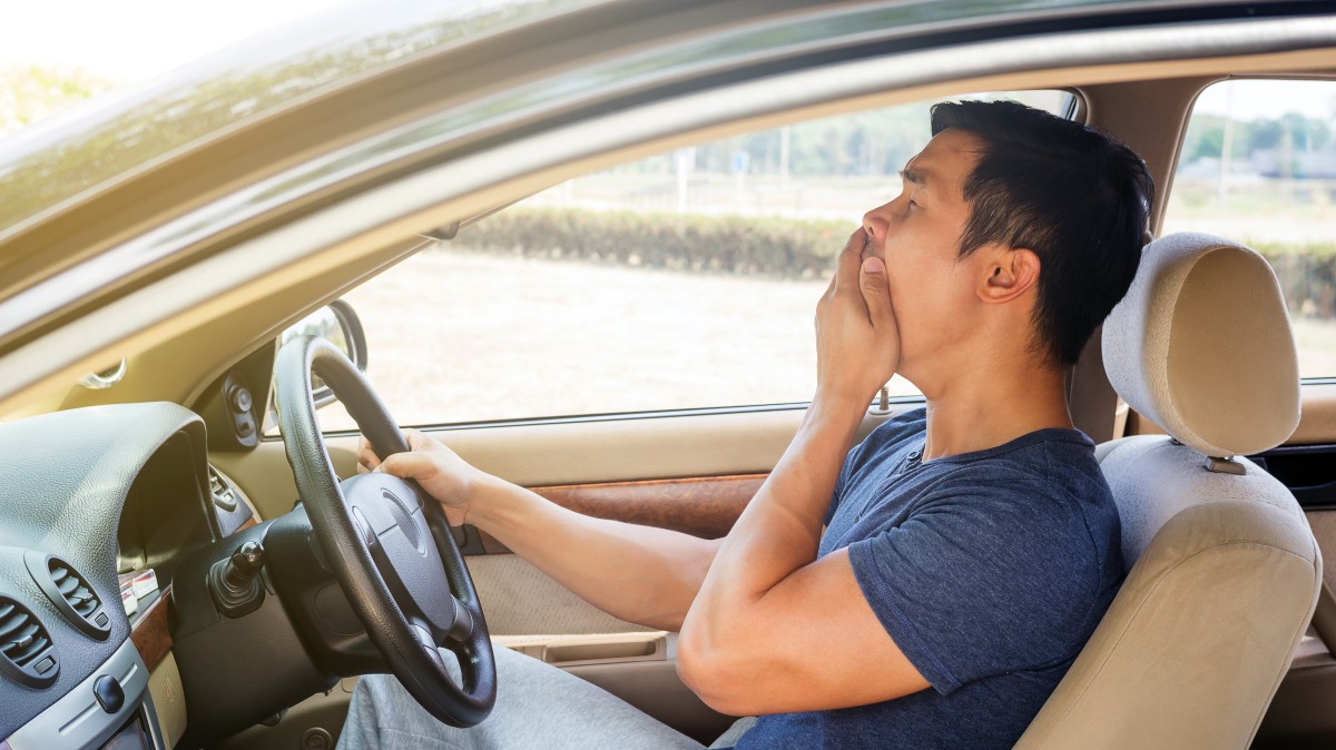 a man yawning while driving