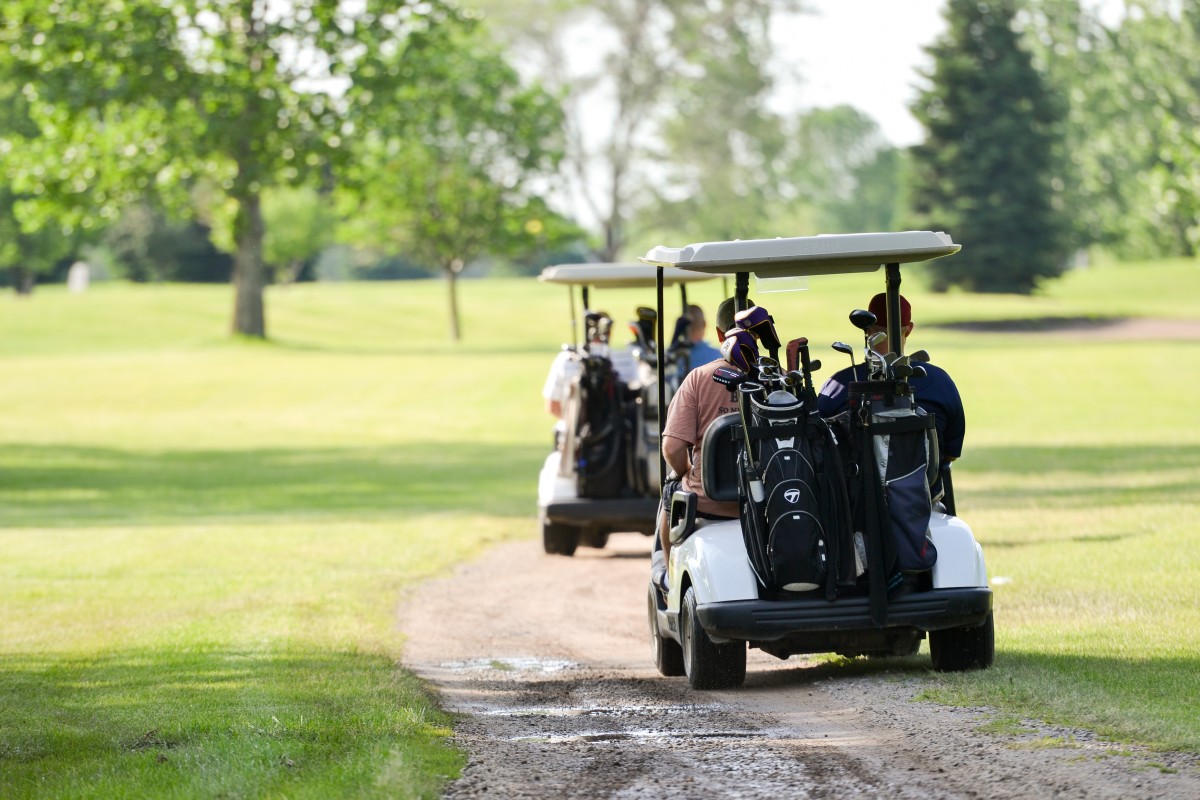 folks riding on golf carts to the next hole