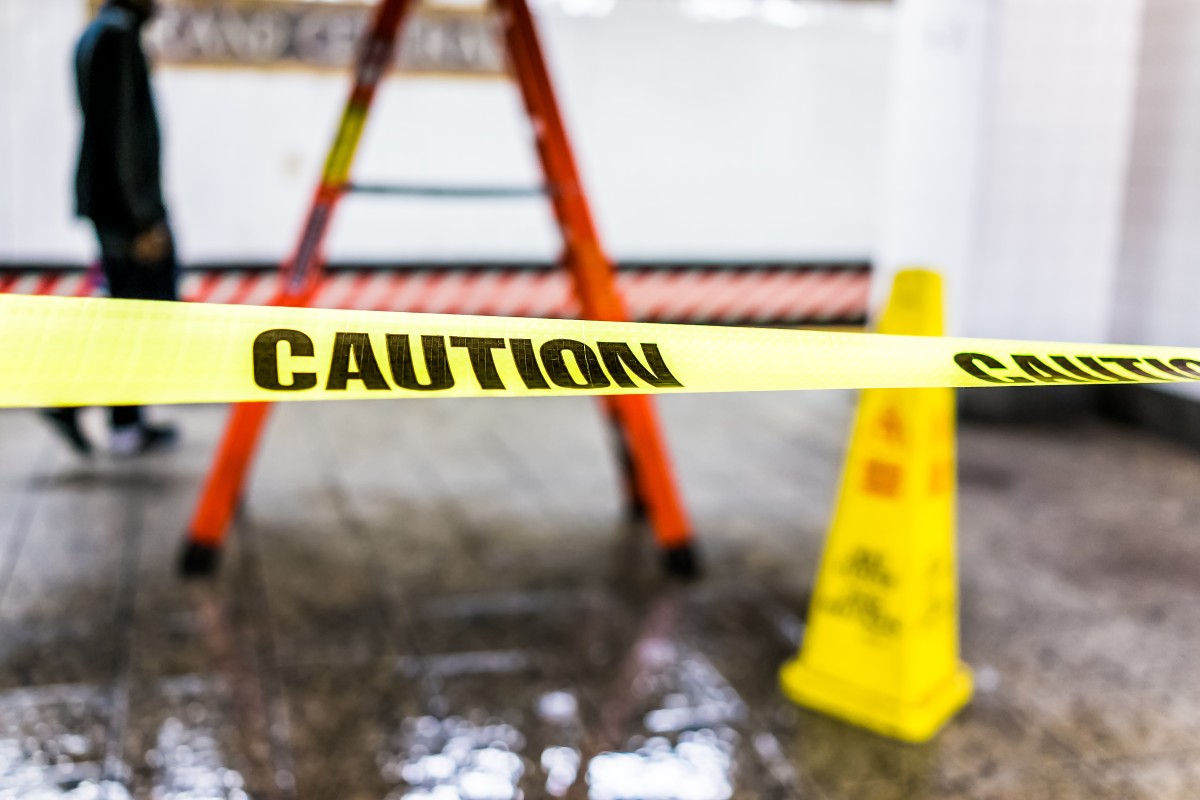 AdobeStock_194045659 Caution tape and a wet floor sign
