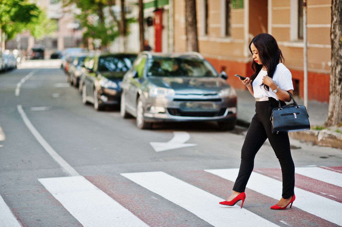 A woman crossing a road while on the phone