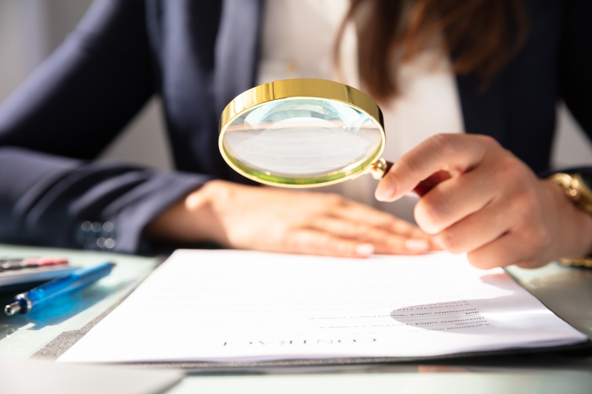 someone examining a document with a magnifying glass