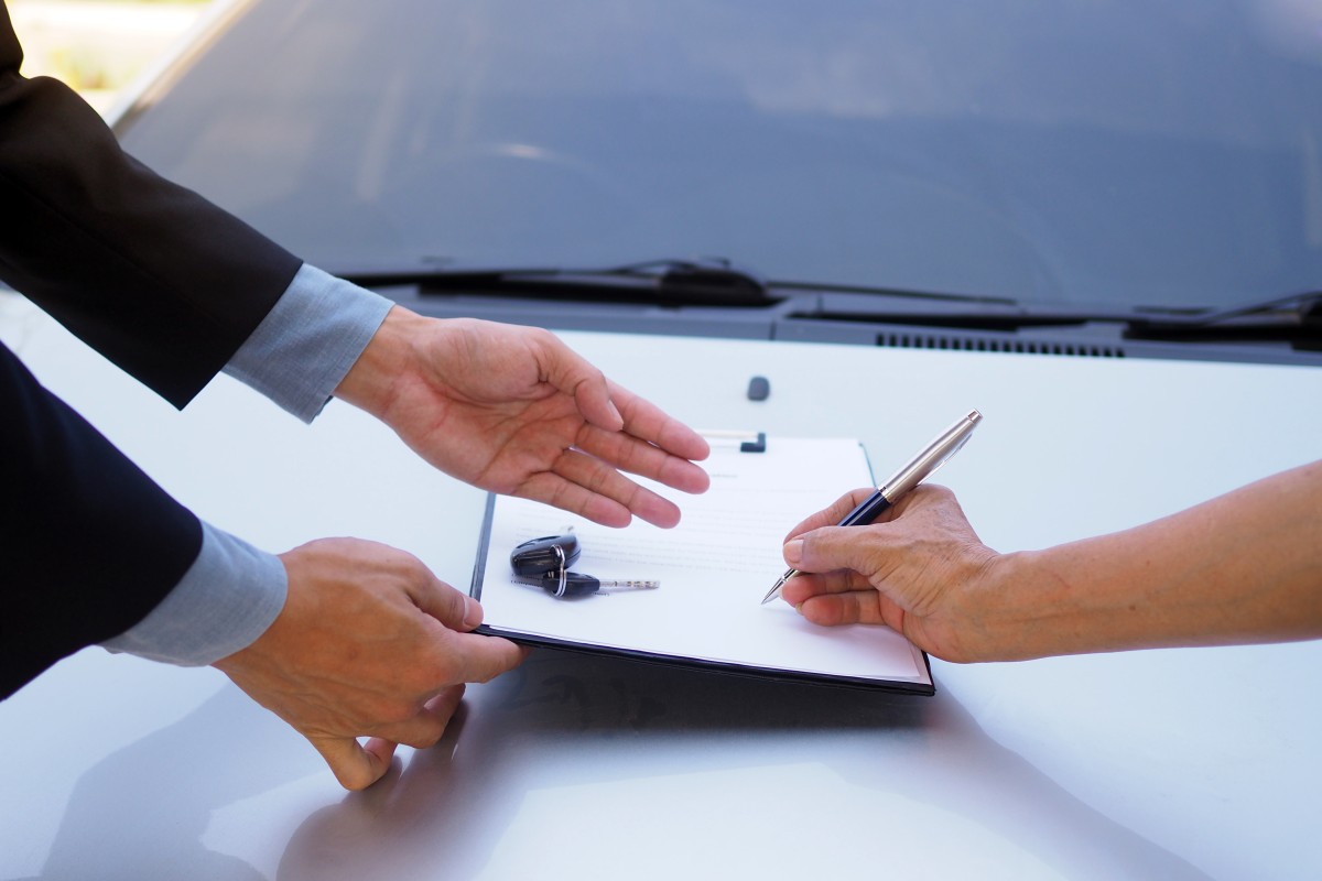 someone signing purchase agreement of a car.