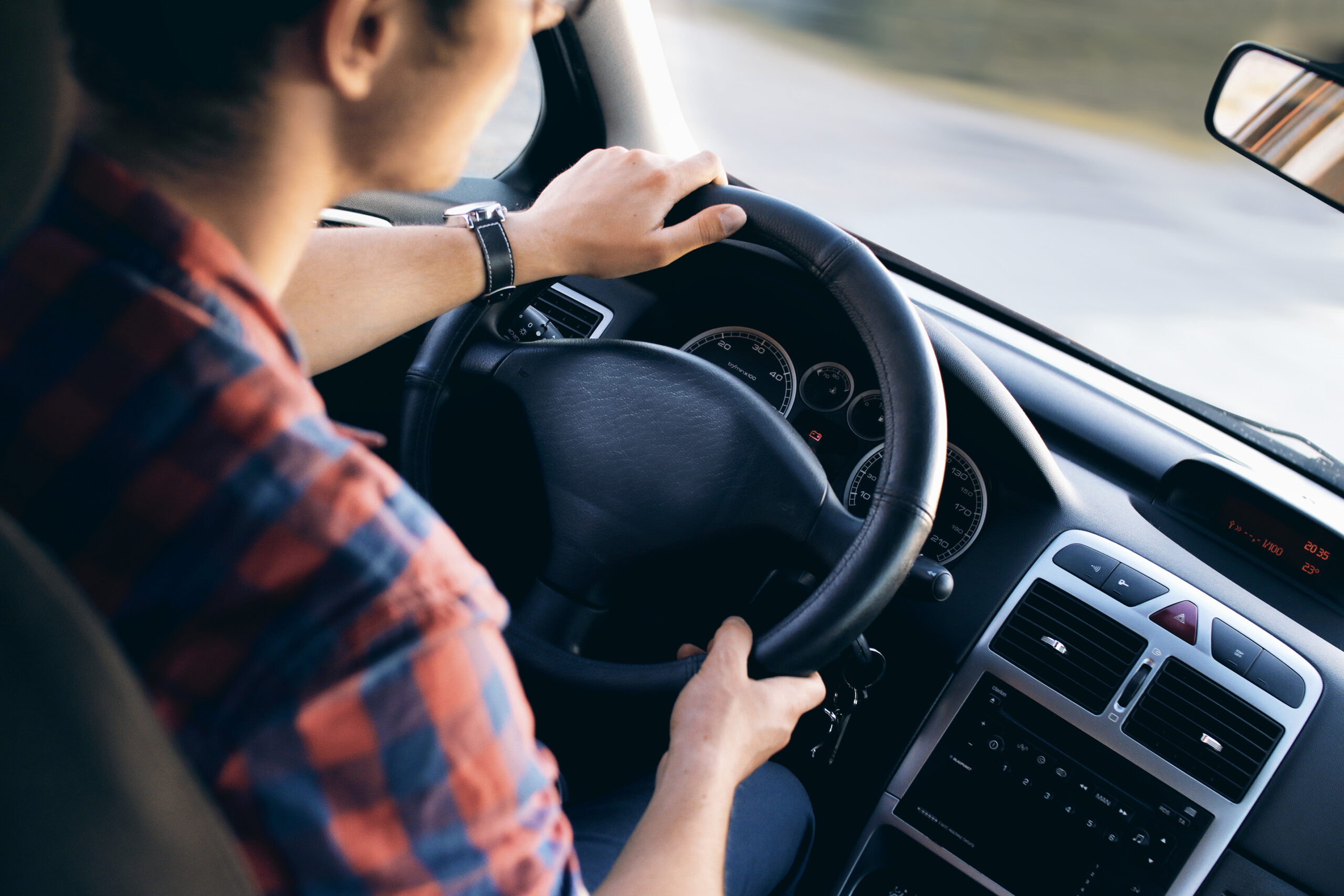 Young driver in his shirt in a nice modern car in motion Man driving car