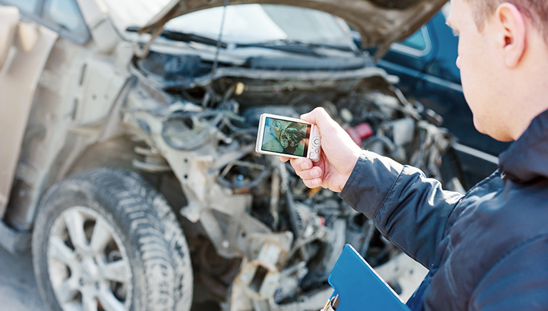 Someone taking a photo of the damage to their car after an accident