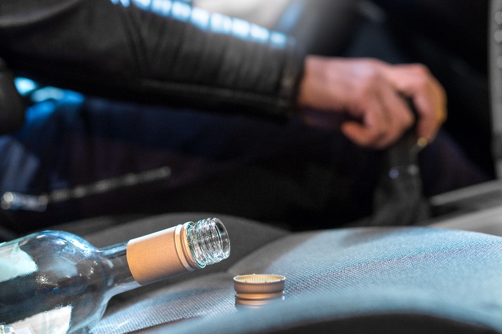 Someone driving with a empty bottle of booze in their passenger seat