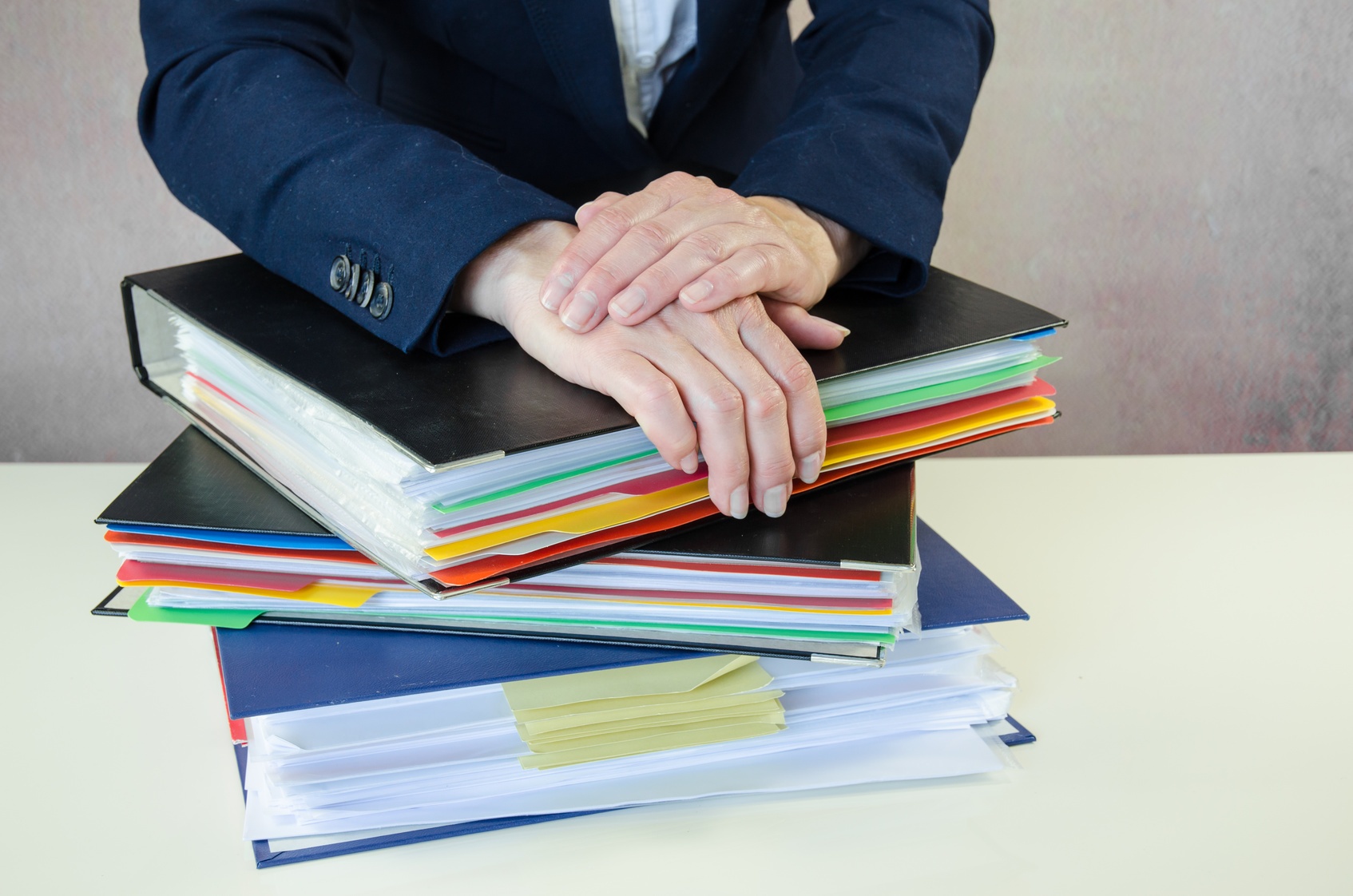 Lawyer_resting_hands_on_pile_of_paperwork_evidence_binders Lawyer_resting_hands_on_pile_of_paperwork_evidence_binders