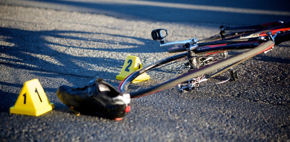 A bicycle on the street, ith a single shoe next to it.