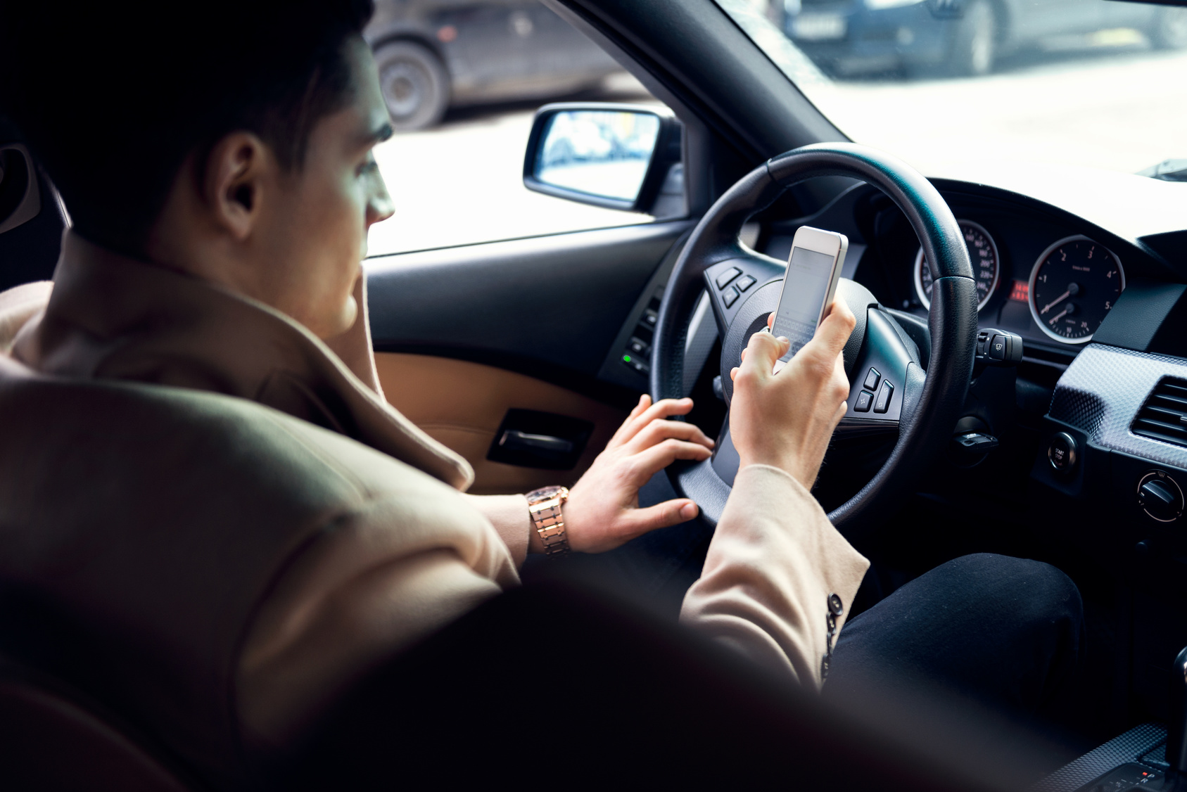Stylish young man using mobile phone ih the car.