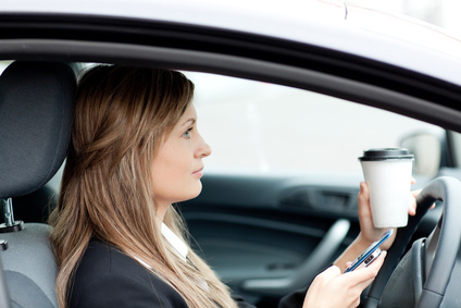 Blond businesswoman sending a text while driving Blond businesswoman sending a text while driving to work