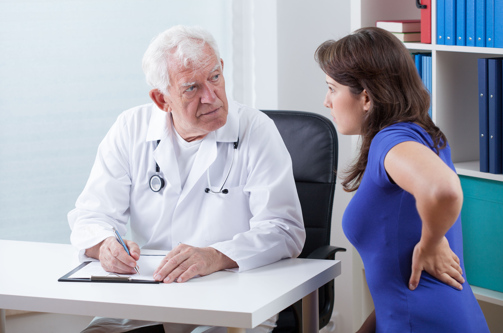 Pain in the back Woman with pain in the back at senior doctor's office
