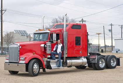 Woman truck driver on the step A pretty woman prepares to pre-trip inspect her truck.