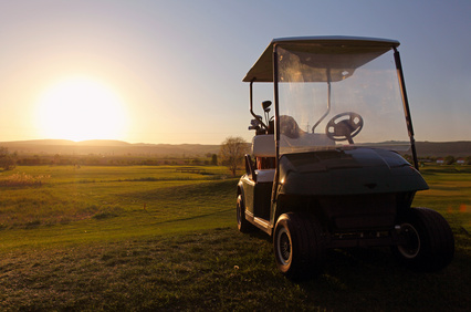 Golf cart over nice green and sunset Golf cart over nice green and sunset