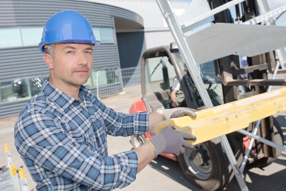 A worker loading lumber into a lift