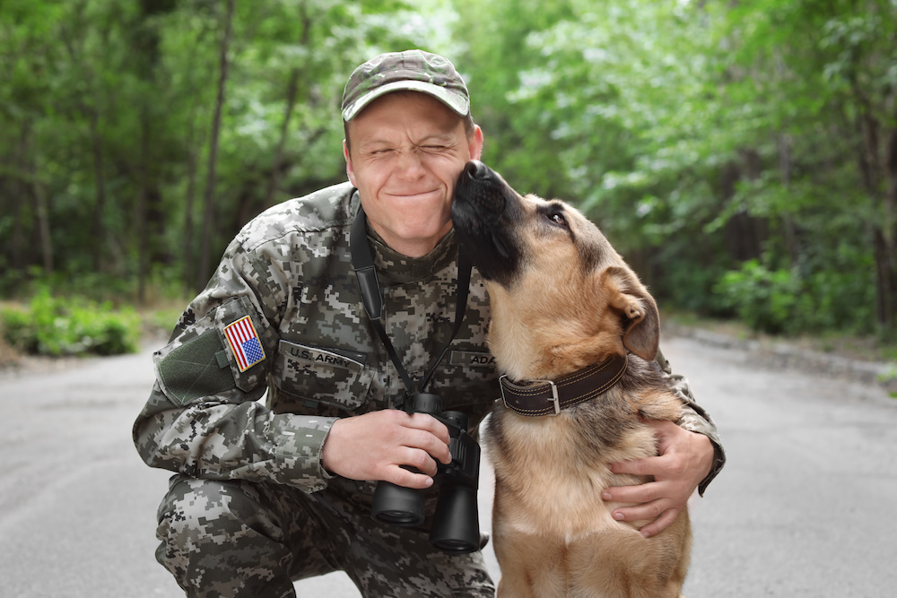 Man in military uniform with German shepherd dog, outdoors
